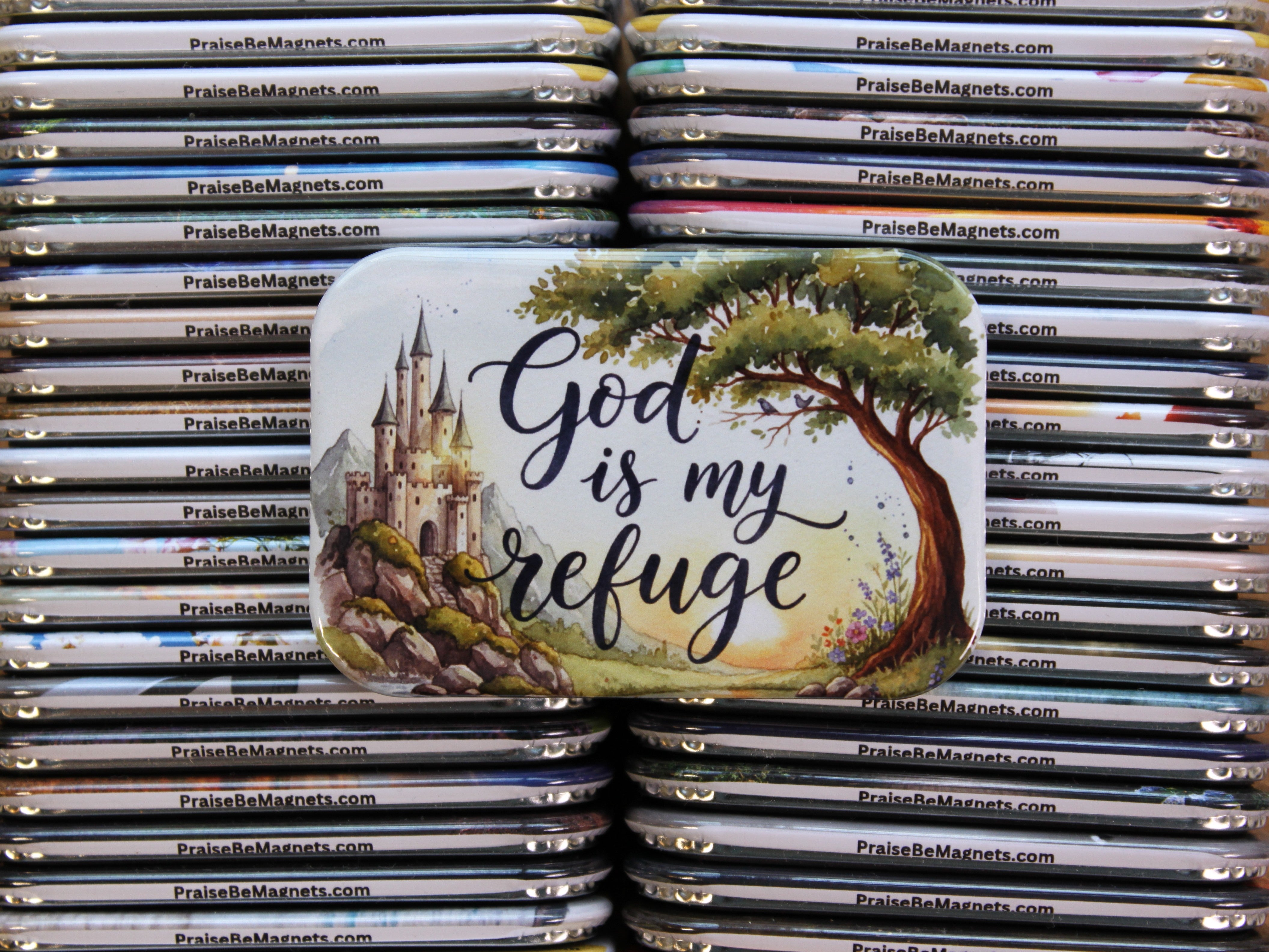 Stack of 'PraiseBeMagnets' with a prominent magnet featuring a castle, tree, and 'God is my refuge' text.