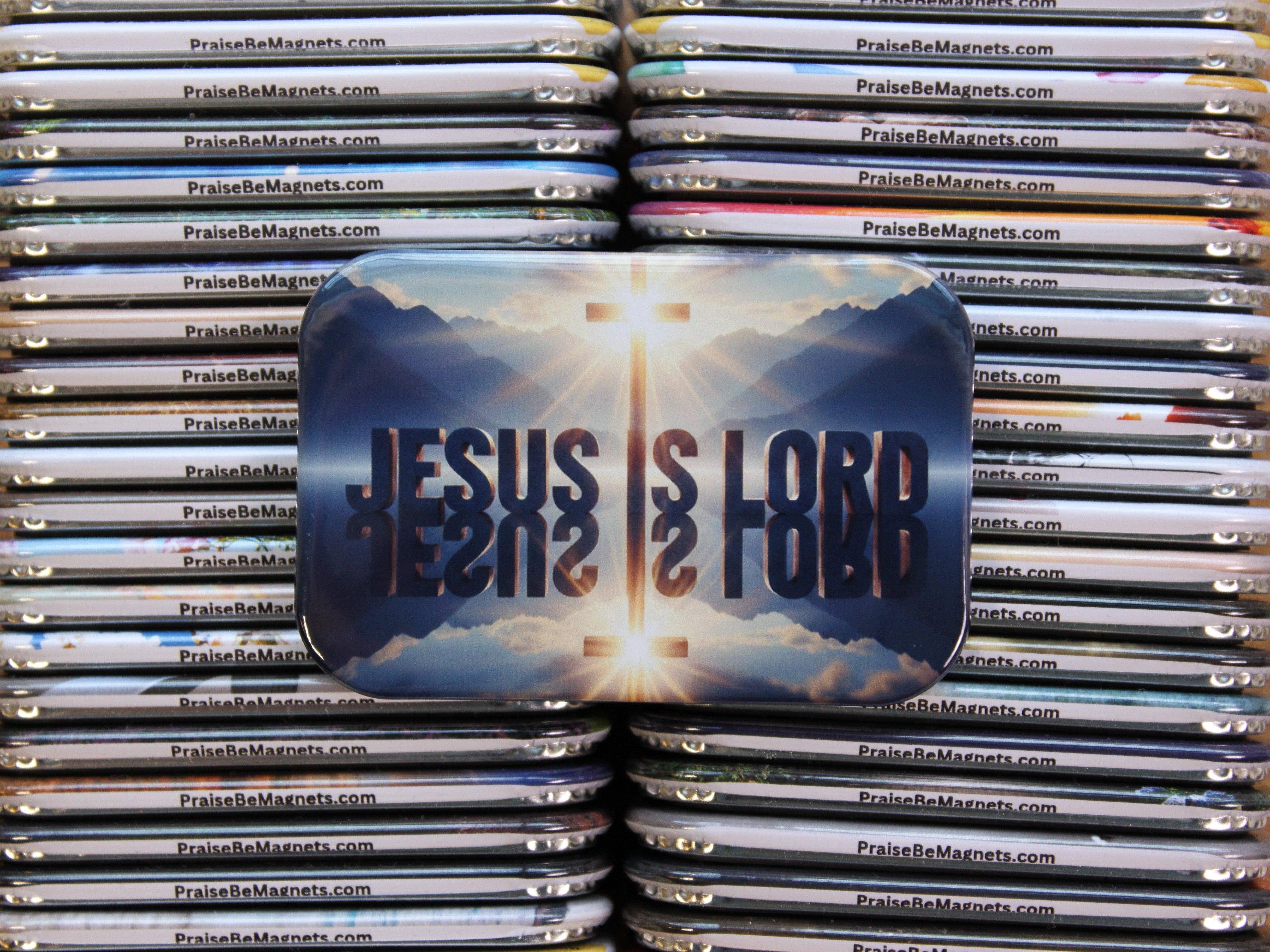Stack of 'Jesus is Love' magnets with a cross and sun design.