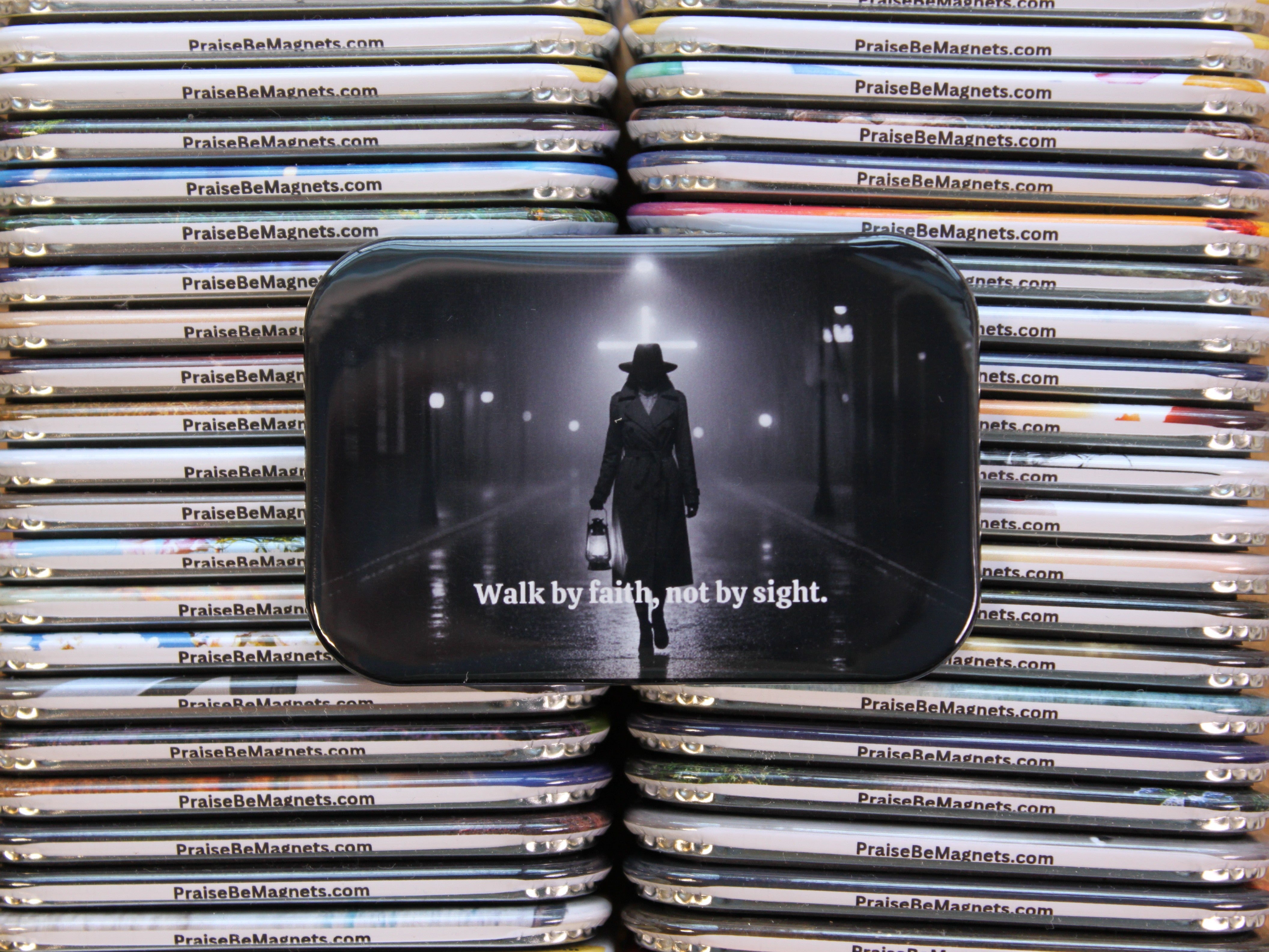 Stack of metal magnets with a central magnet featuring a silhouette and text, surrounded by other magnets.