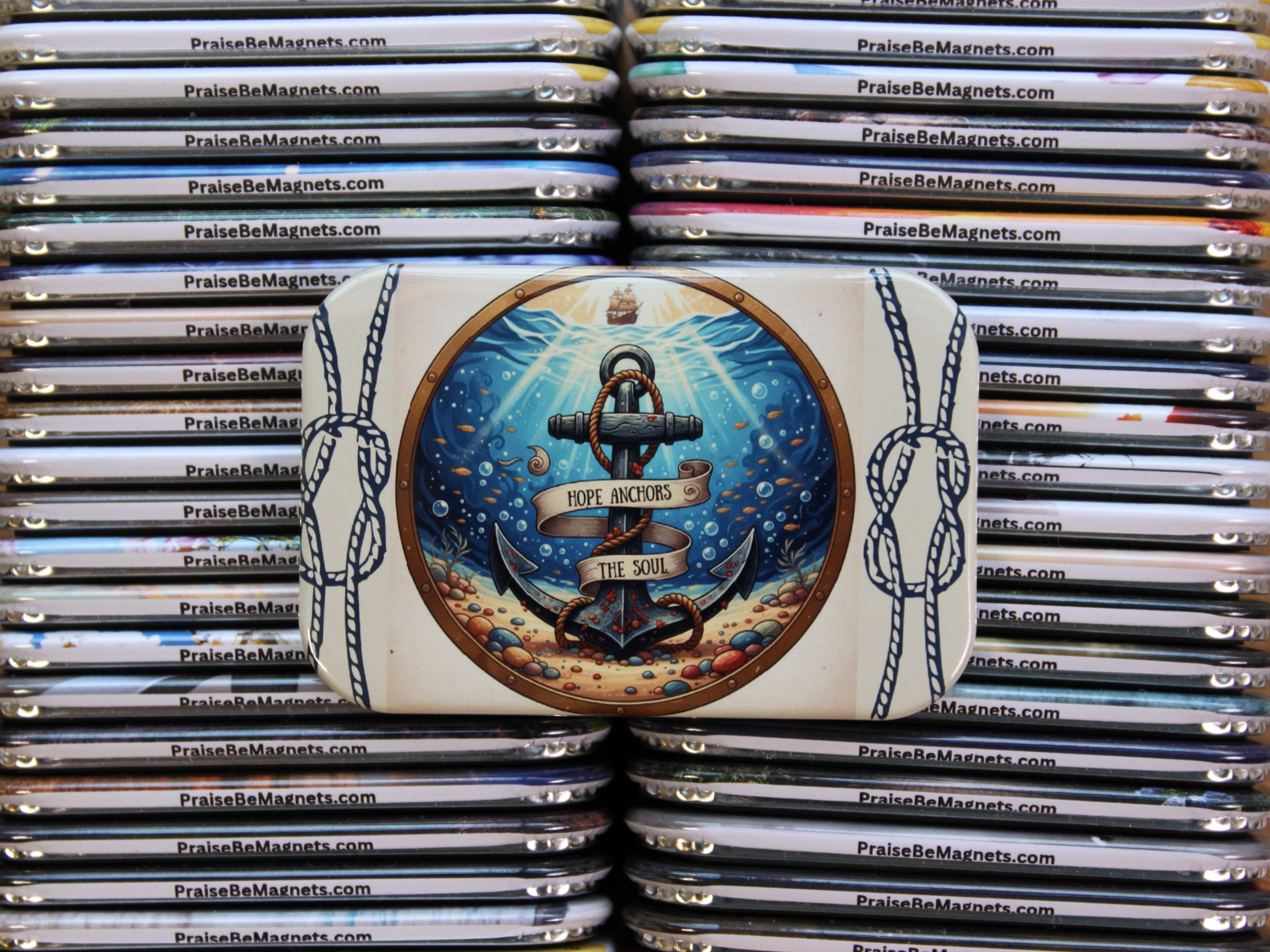 Stack of 'Praise Be Magnets' with a decorative magnet featuring an anchor design.