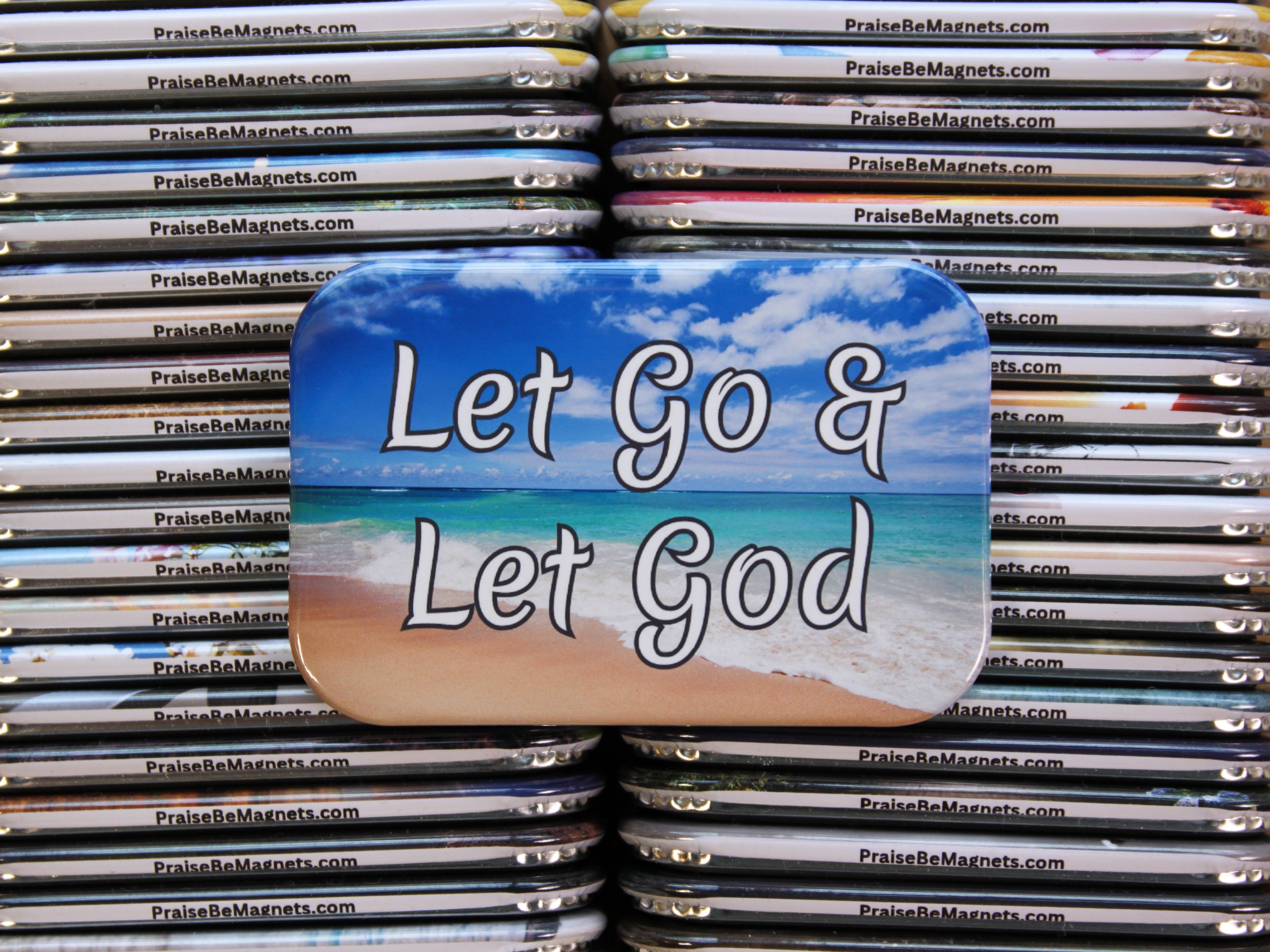 Stack of metal magnets with 'Let Go & Let God' text and beach design