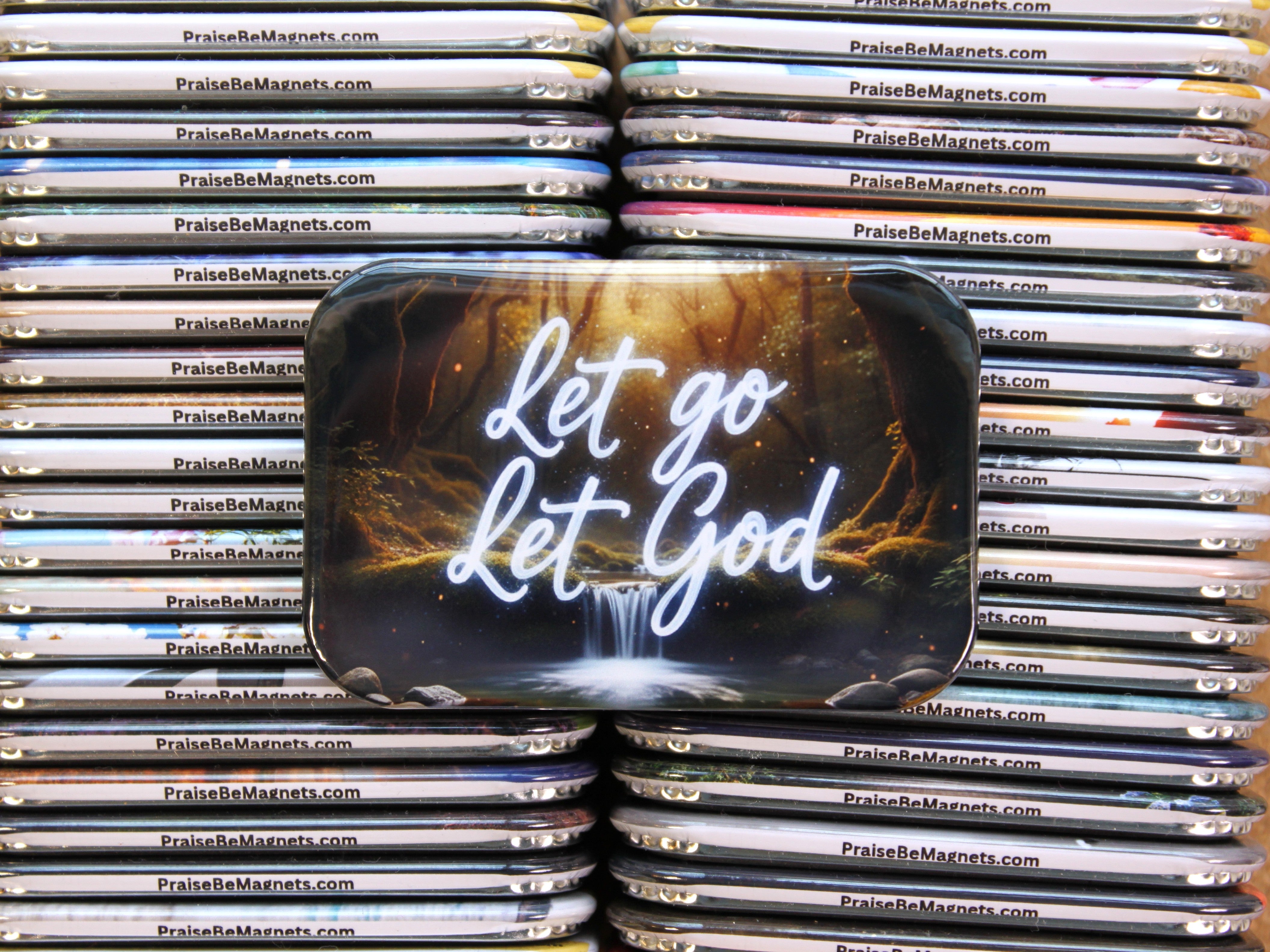Stack of 'Let go Let God' magnets with a scenic design.