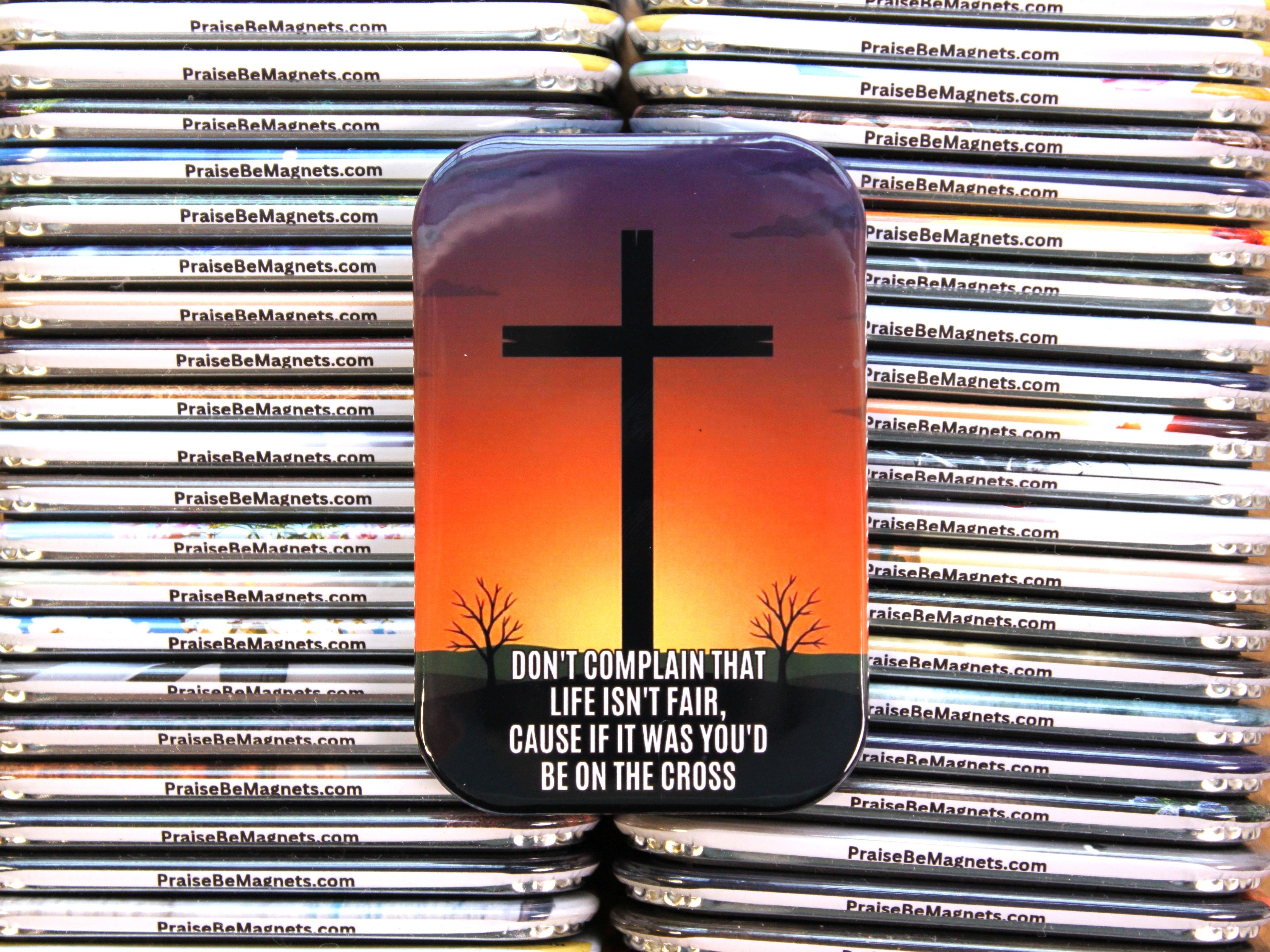 Magnet with cross design and motivational quote on a stack of similar magnets.