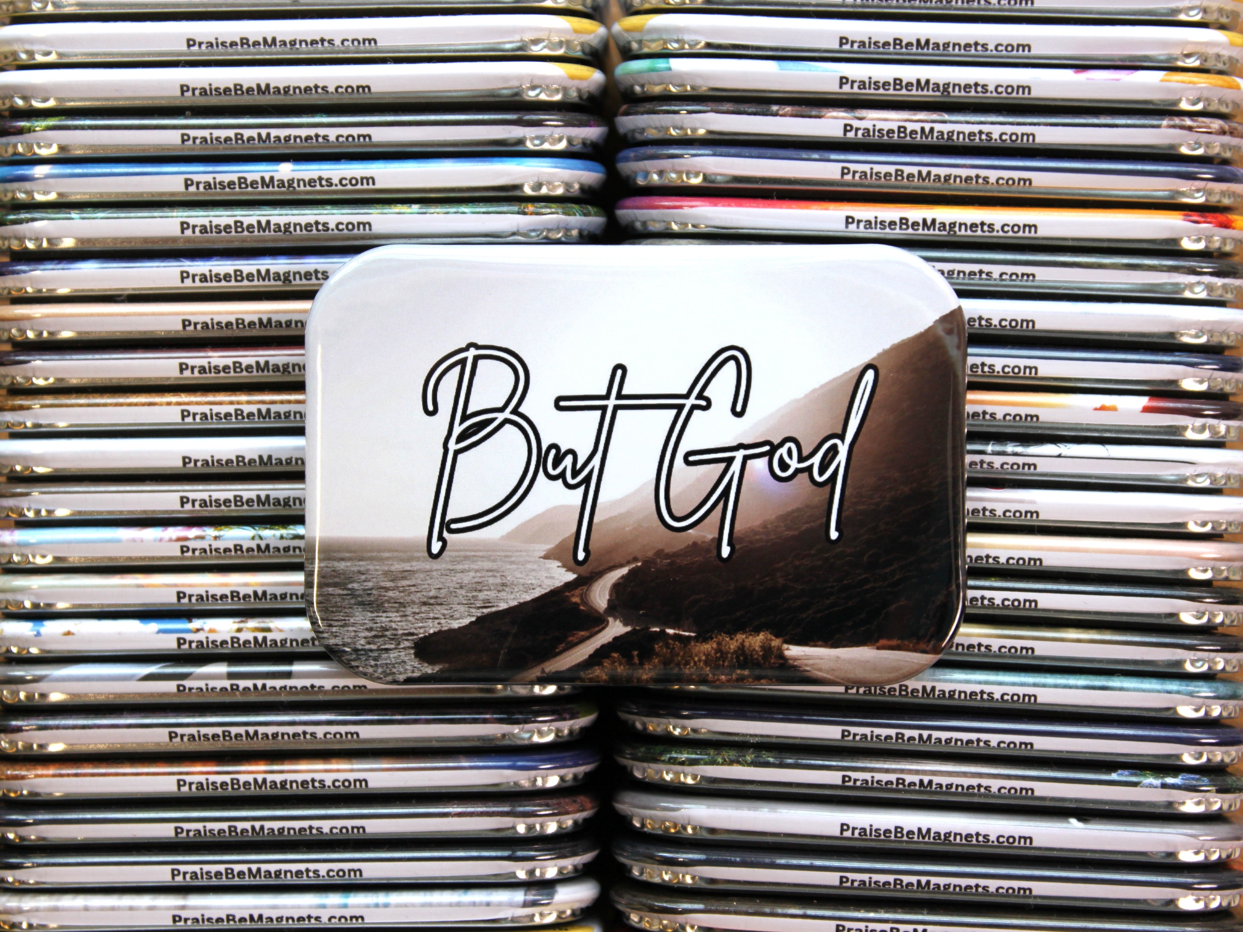 Stack of metal magnets with 'But God' text on a white background