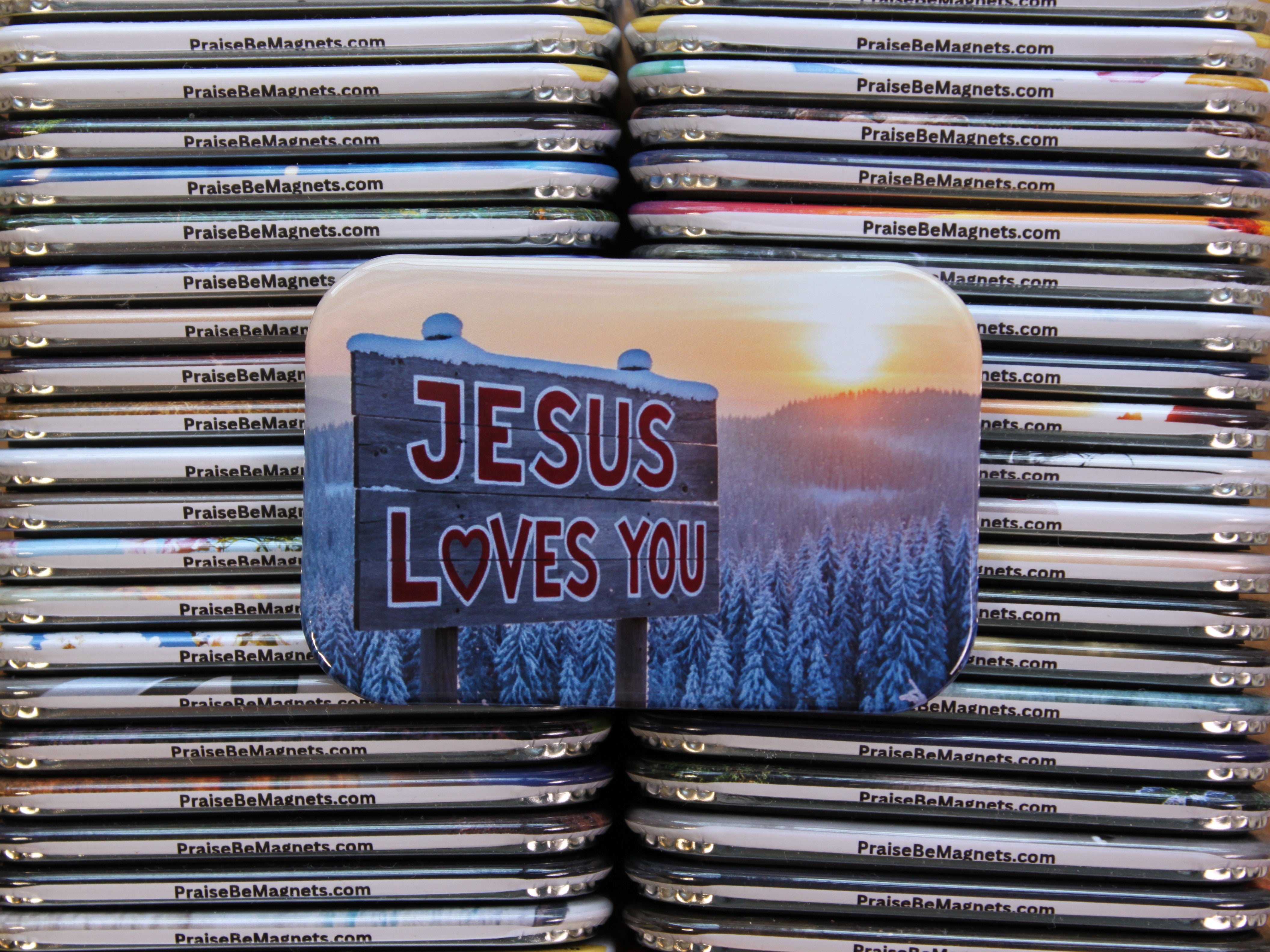 Stack of 'PraiseBeMagnets' with a prominent 'Jesus Loves You' magnet on top.