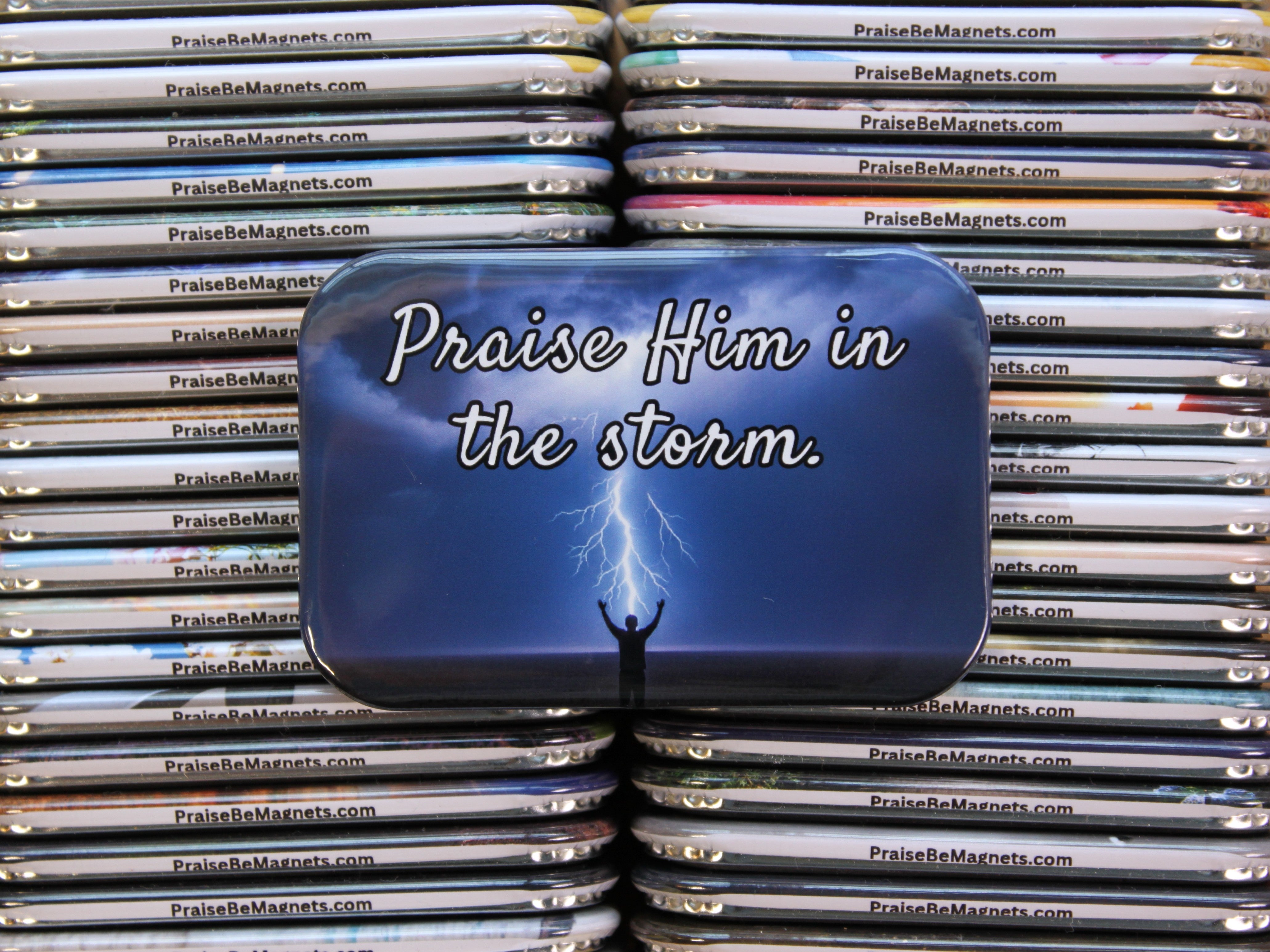 Stack of 'Praise Him in the Storm' magnets with a blue background