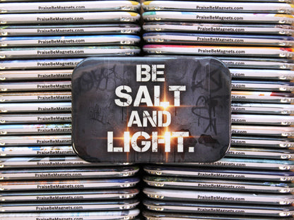 Stack of metal magnets with 'Be Salt and Light' text on a reflective surface.