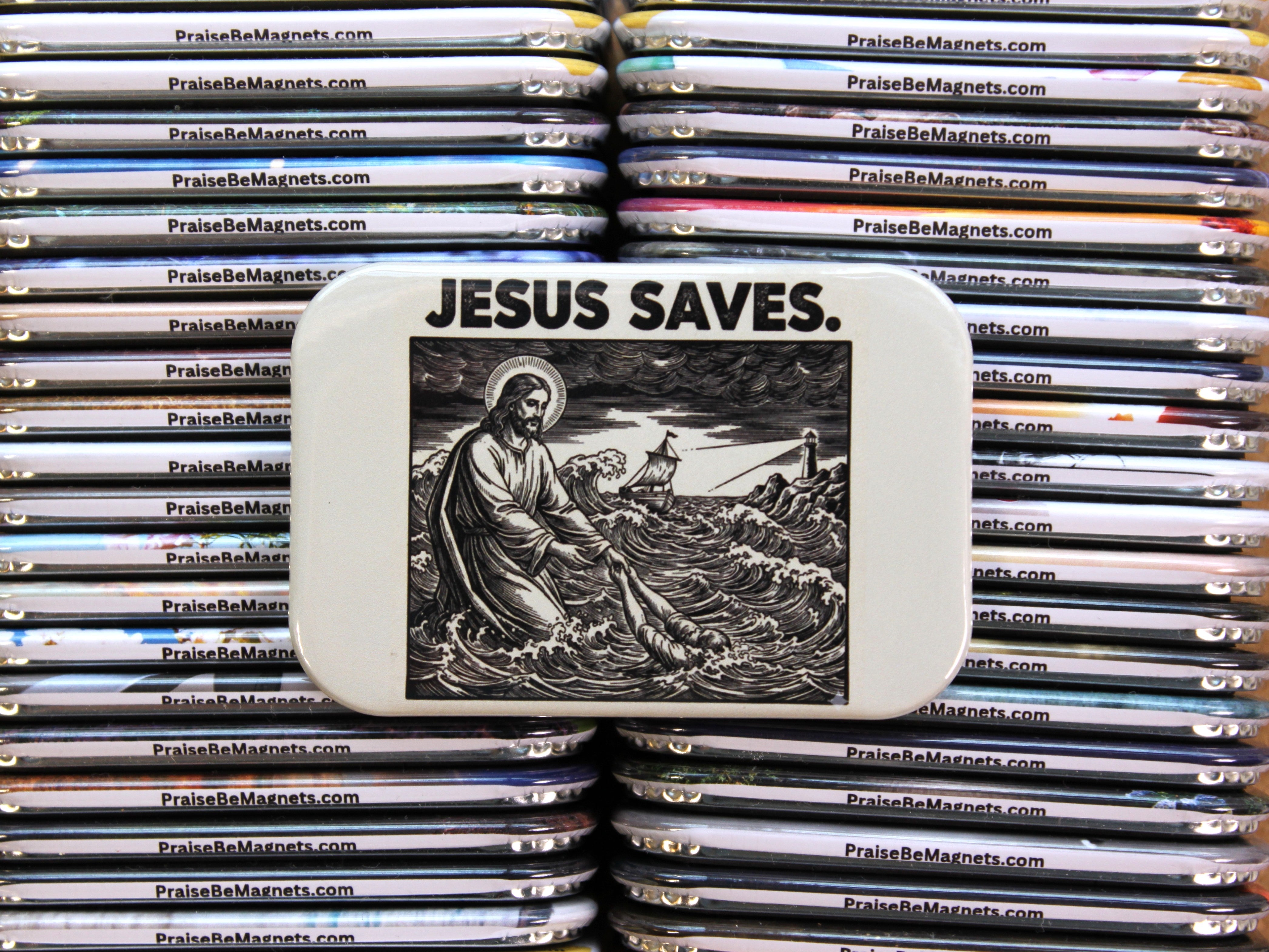 Stack of 'Praise Be Magnets' with a prominent magnet featuring an image of Jesus and the text 'Jesus Saves'.