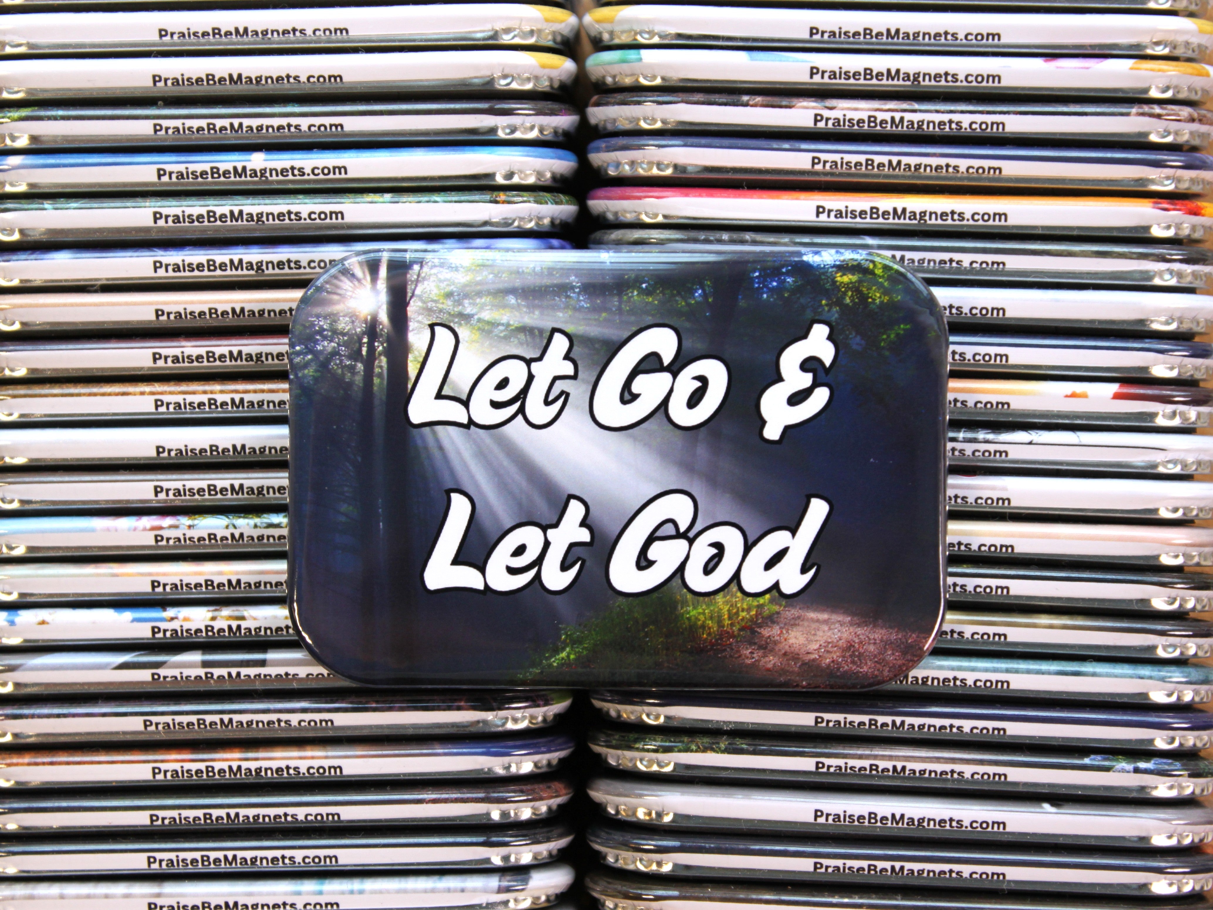 Stack of metal containers with 'Let Go & Let God' text on a reflective surface.