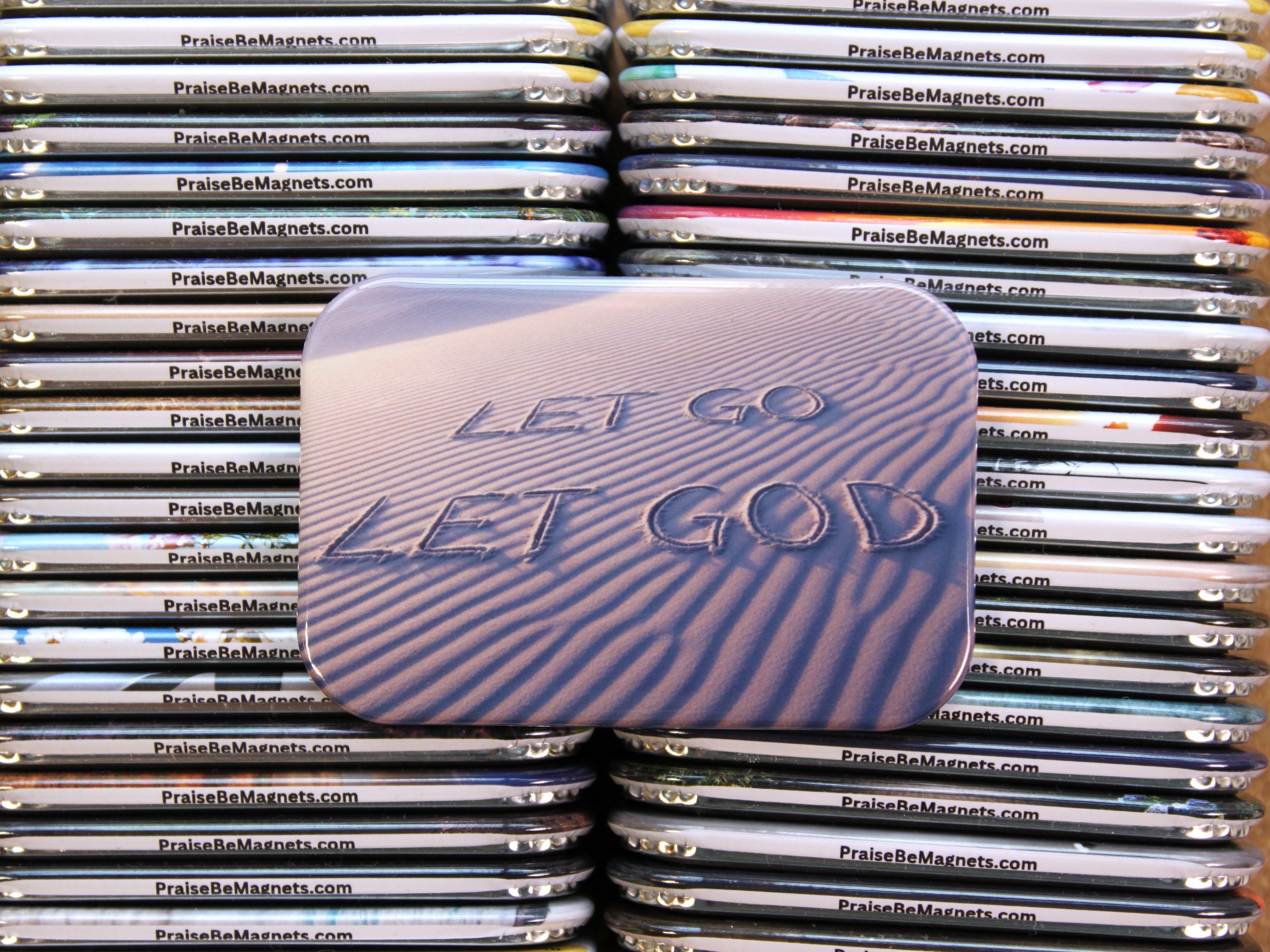Stack of 'Praise Be Magnets' with a prominent 'Let Go Let God' magnet in the center.