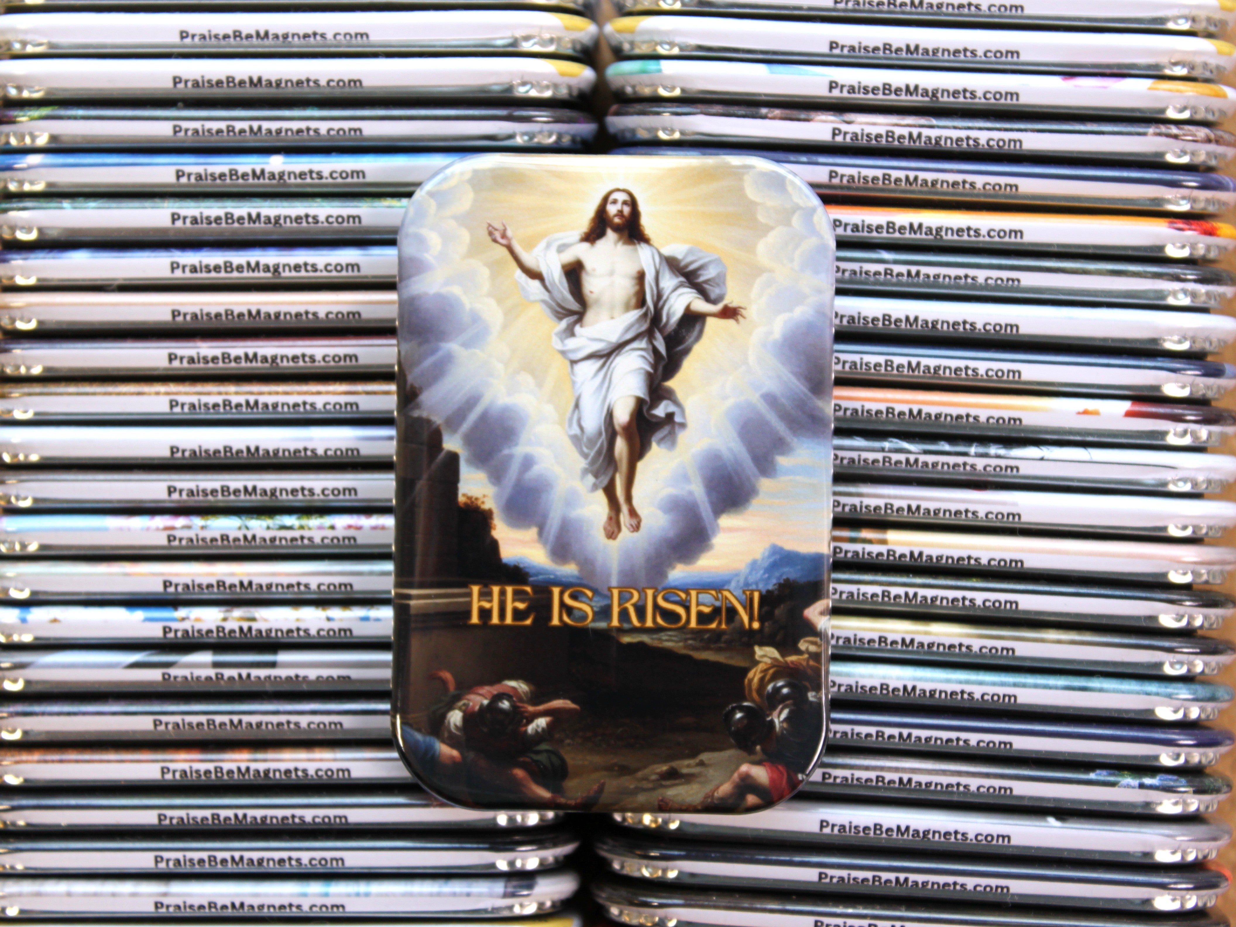 Stack of 'He Is Risen' religious magnets with a depiction of Jesus on a cloud.