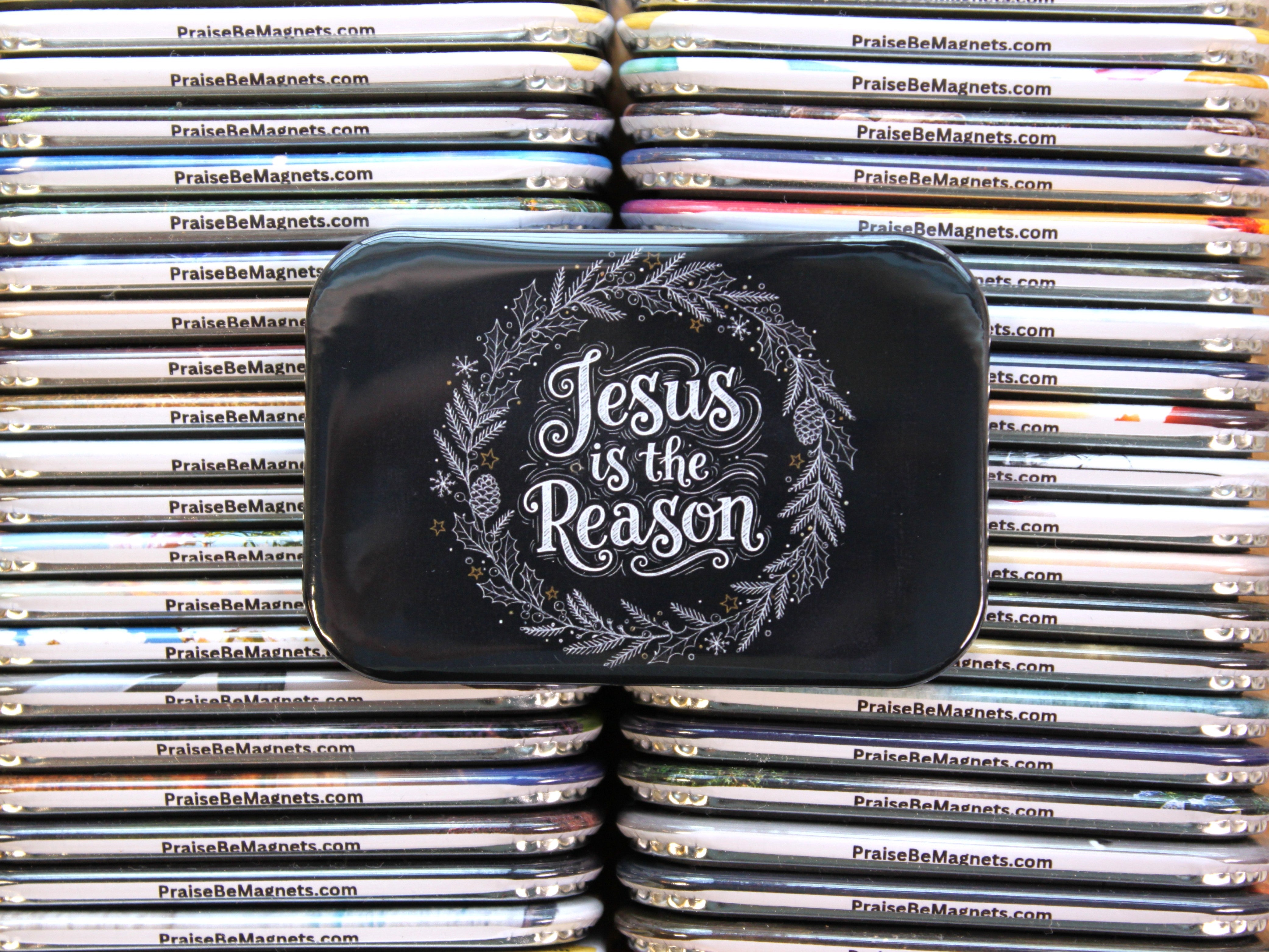 Stack of metal magnets with 'Jesus is the Reason' text on a black tin lid.