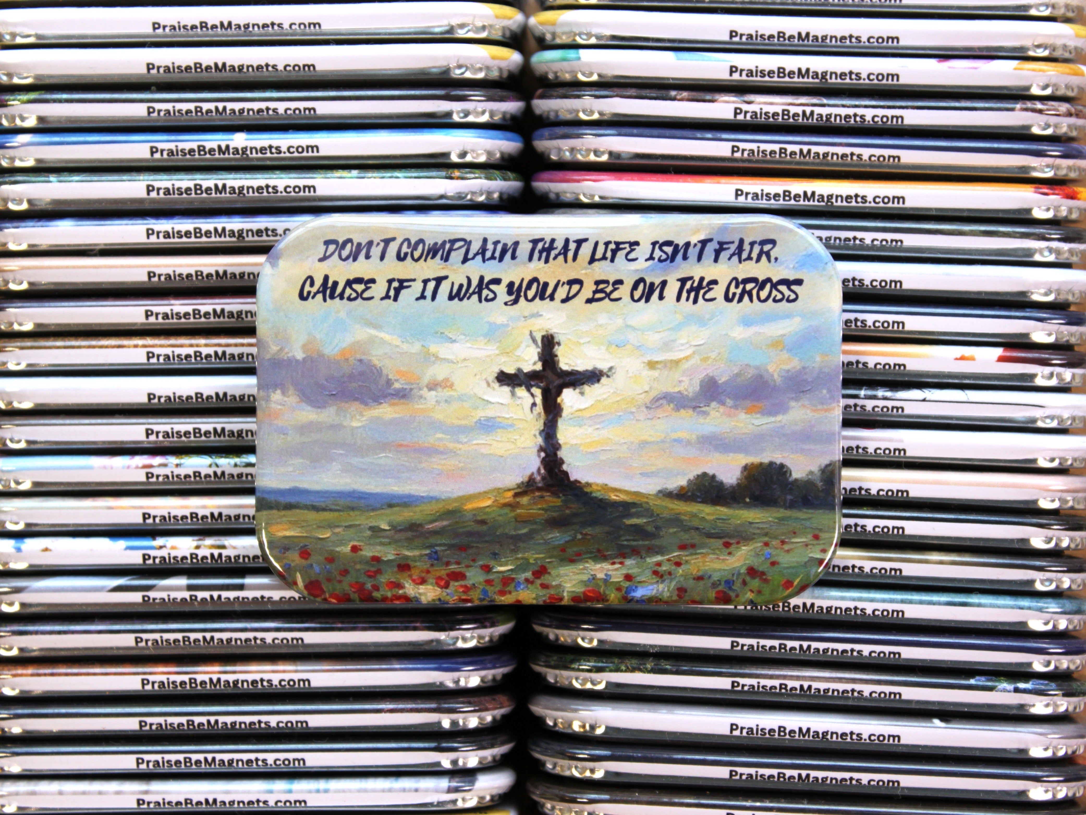 Stack of PrayReMagnet products with a magnet featuring a cross and landscape design.