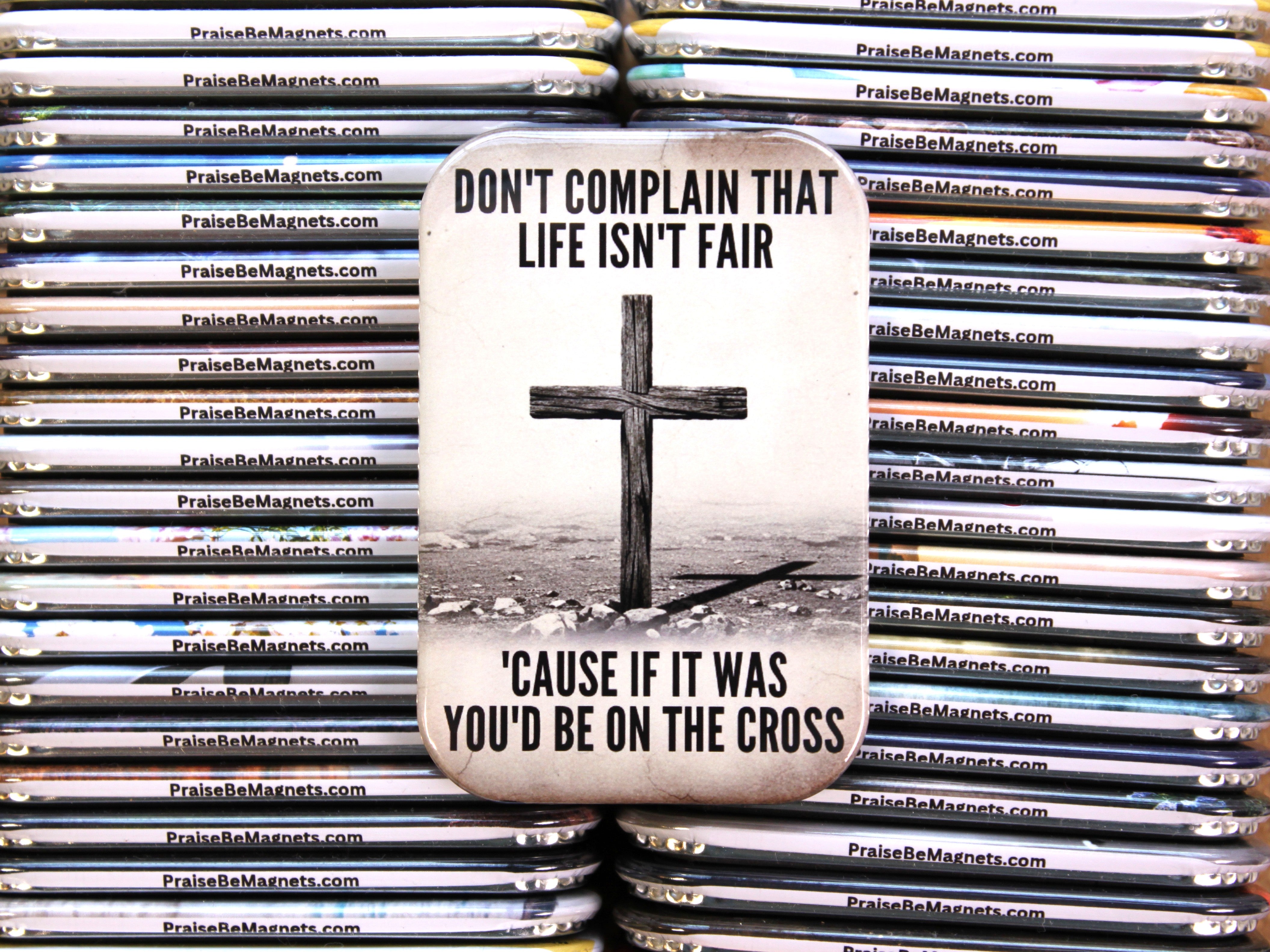 PraiseBeMagnets with a cross and motivational quote on a stack of similar magnets.
