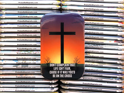 Magnet with cross design and motivational quote on a stack of similar magnets.