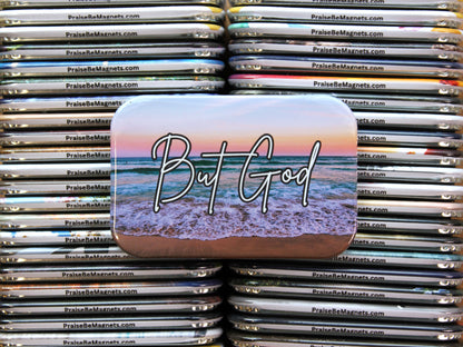 Stack of 'But God' beach-themed magnets with a website address.
